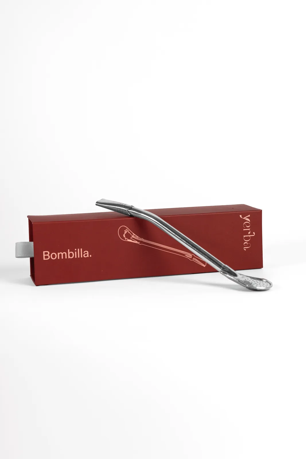 Stainless steel bombilla resting on its red Yerba box